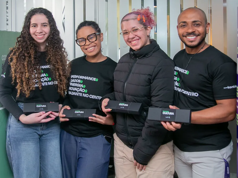 Quatro colaboradores da Kontrip segurando os brindes da campanha de cultura