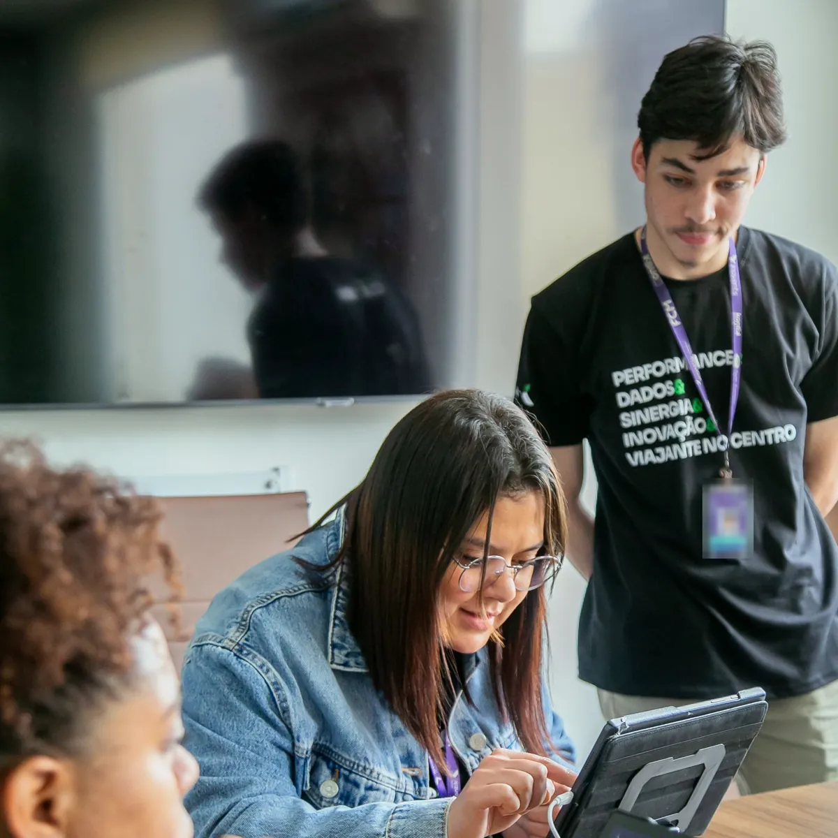 Colaboradores da Kontrip usando a plataforma em um tablet, em sala de reunião